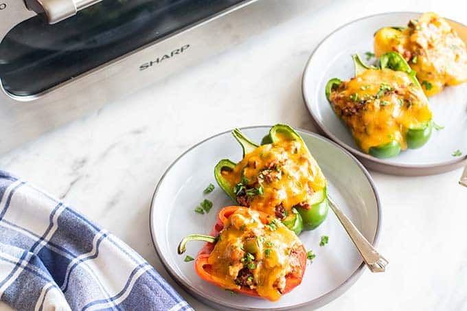 Two plates with stuffed bell peppers in front of the Sharp Superheated Steam Countertop Oven.