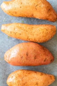 A close up of sweet potatoes rubbed with salt ready to be baked.