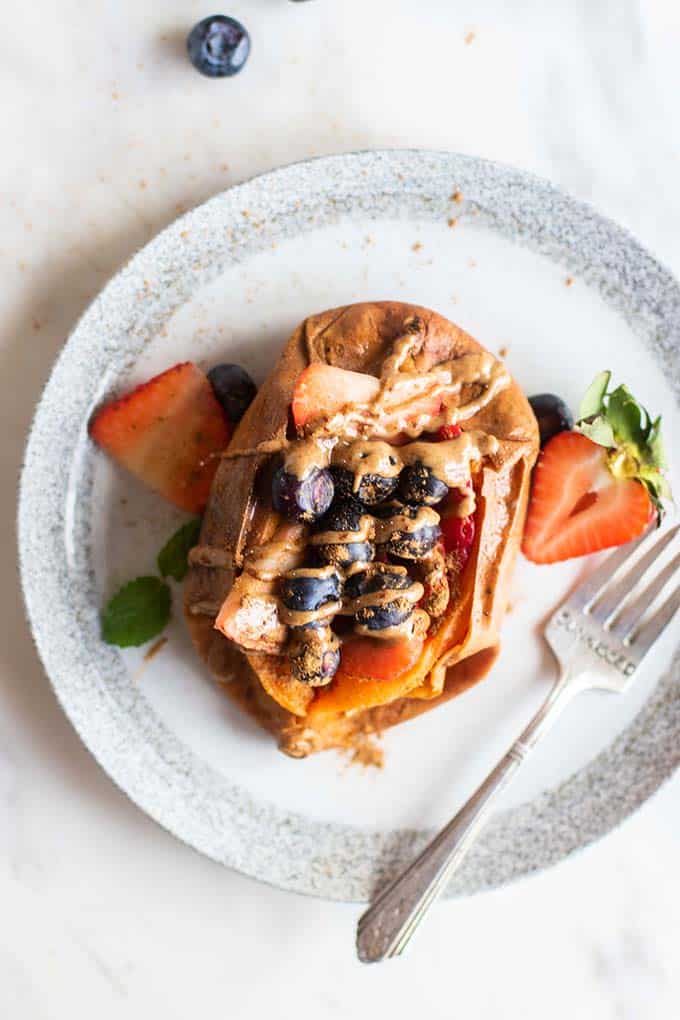 A baked sweet potato stuffed with berries and drizzled with almond butter.
