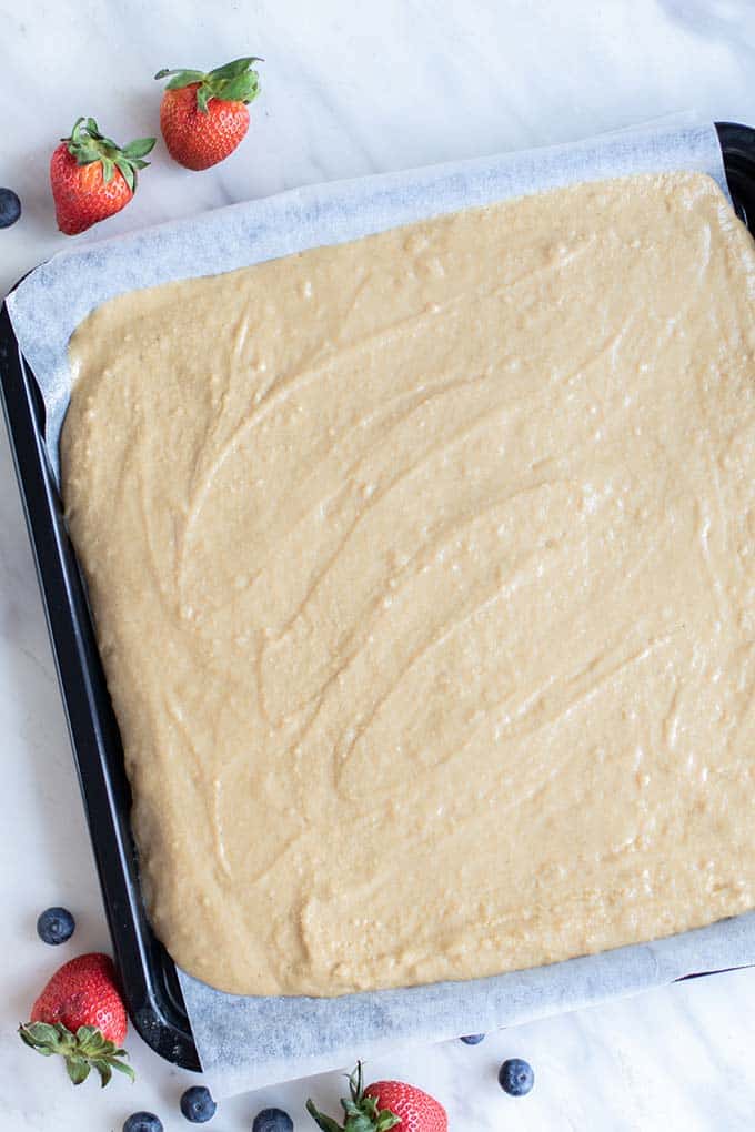 A baking tray lined with parchment, and covered in a gluten free pancake batter.
