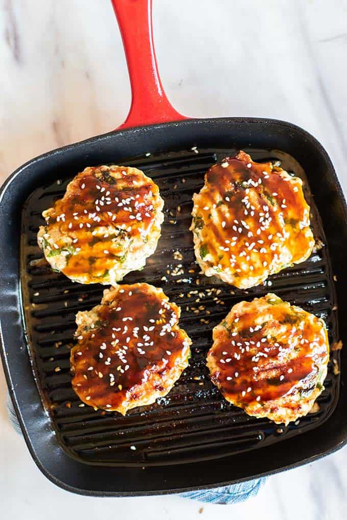 A grill pan with 4 grilled chicken burgers.