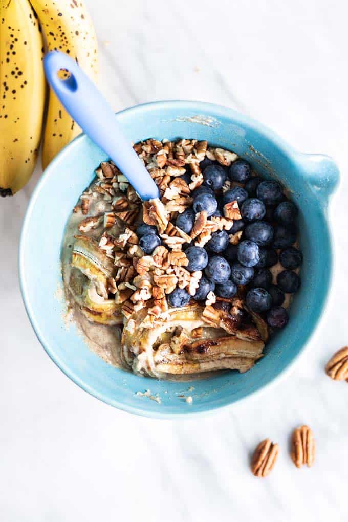 Banana bread batter in a bowl with caramelized bananas, pecans, and blueberries.