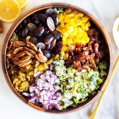 A top view of a broccoli salad with bacon, grapes, pecans, raisins, and peppers.