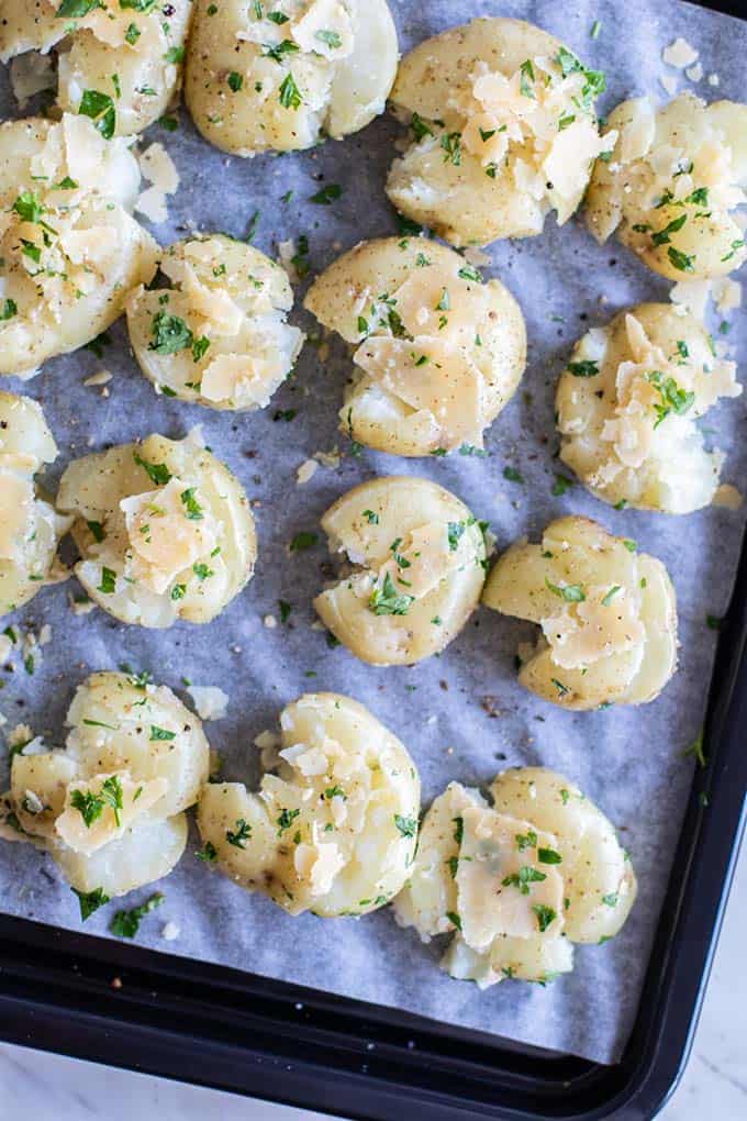 A close up look at how to smash potatoes on a baking tray.