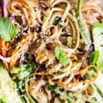 A close up view of a thai noodles dish with julienne zucchini, carrots and cabbage.