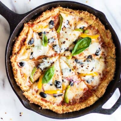 A cast iron skillet with a pizza cooked inside it.