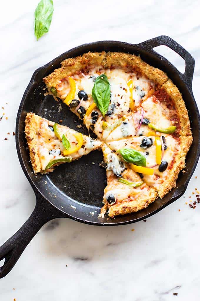 A cast iron skillet with a deep dish cauliflower crust pizza.