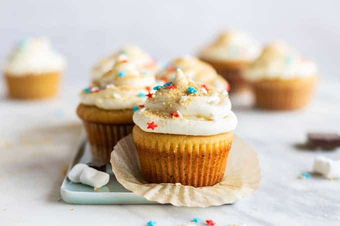A vanilla cupcake with white icing and red, white and blue star sprinkles.