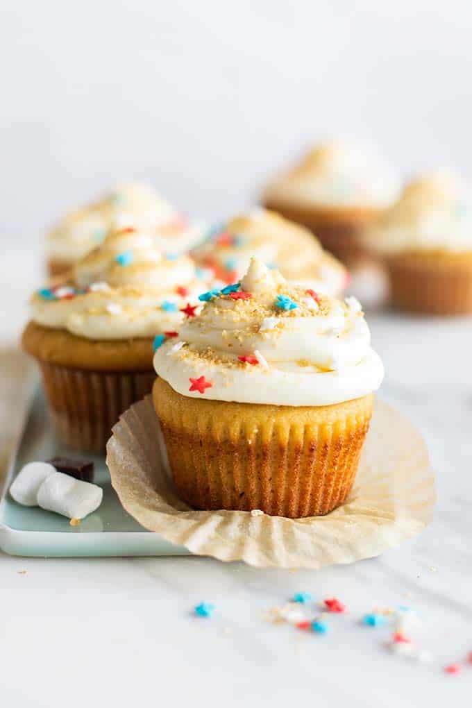 A gluten free vanilla cupcake with white icing and red, white and blue star sprinkles.