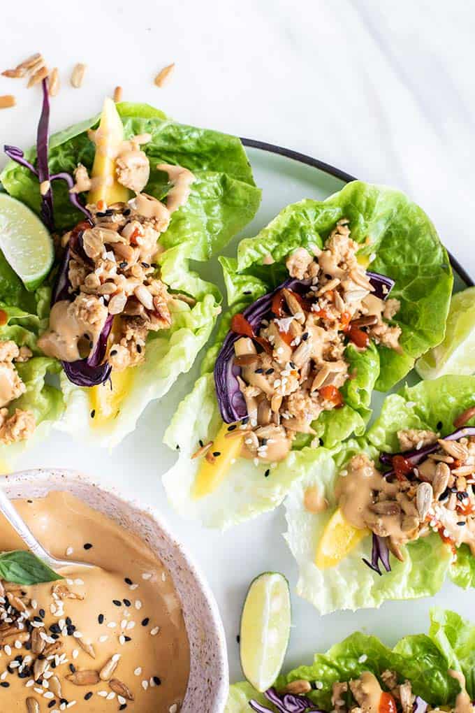 A close up of Thai chicken lettuce wraps next to a pink bowl of SunButter dipping sauce.