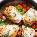 Stuffed chicken breasts garnished with basil and roasted tomatoes.