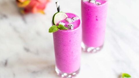 Two dragon fruit smoothies garnished with mint, lime and white dragon fruit,