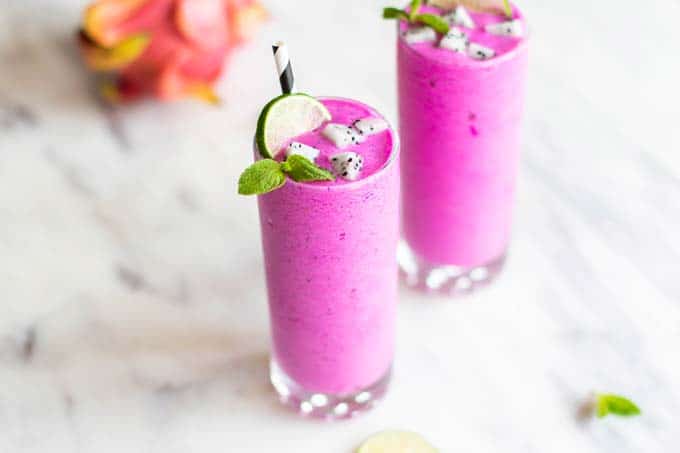 Two dragon fruit smoothies garnished with mint, lime and white dragon fruit,