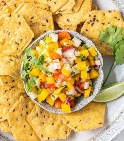 A bowl of multi grain chips with a dish of salsa in the middle.