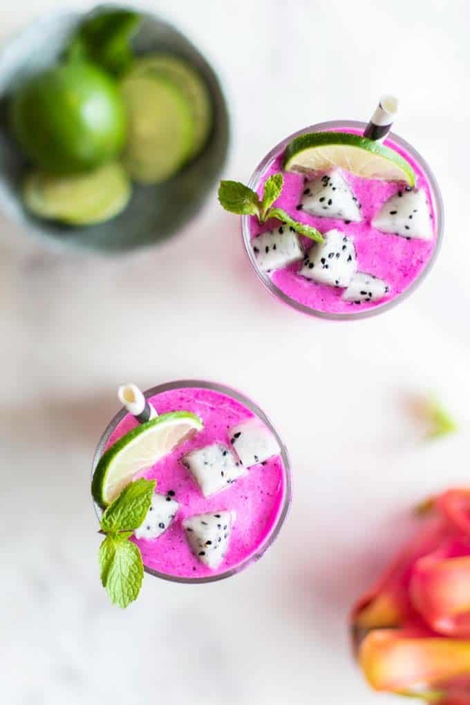 Looking top down at two bright pink dragon fruit smoothies garnished with white dragon fruit.