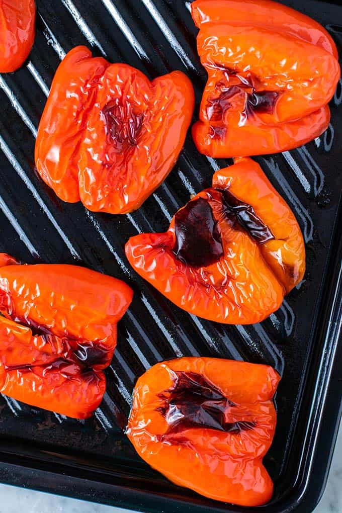 A baking tray with charred red peppers.