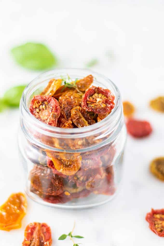 A glass jar filled with colorful sun dried tomatoes.