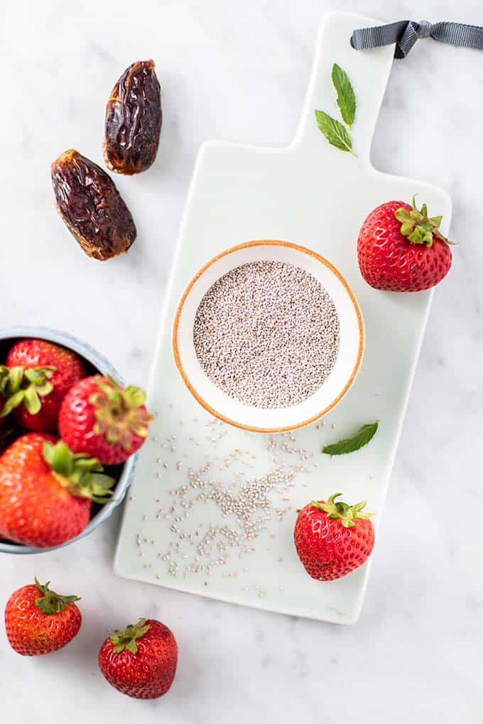 A dish of white chia seeds and some strawberries.