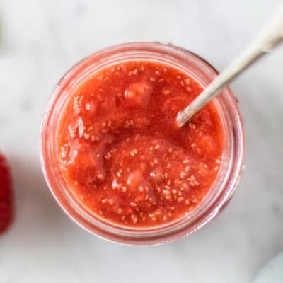 A jar of chia seed jam with a spoon scooping some.