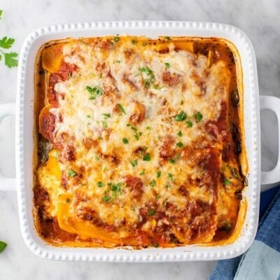 A white casserole pan with a butternut squash lasagna sitting next to a blue towel.