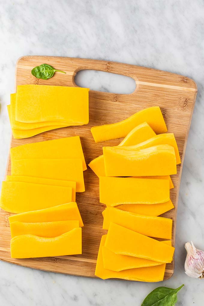 A cutting board with thinly sliced butternut noodles.