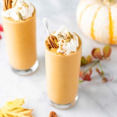 Two pumpkin spice latte smoothies with fall leaves and a pumpkin.