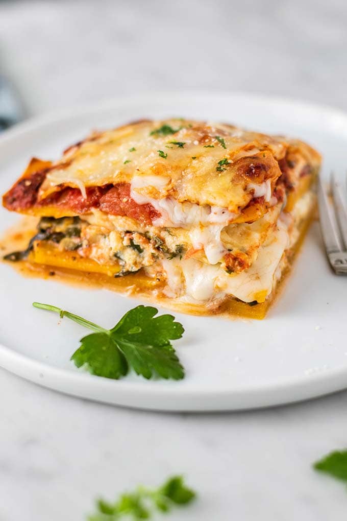 A slice of butternut lasagna with cheese oozing out.