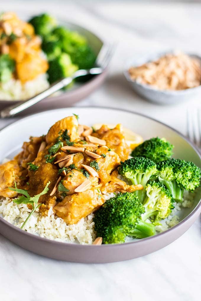 A serving of pumpkin chicken on top of cauliflower rice, next to steamed asparagus.