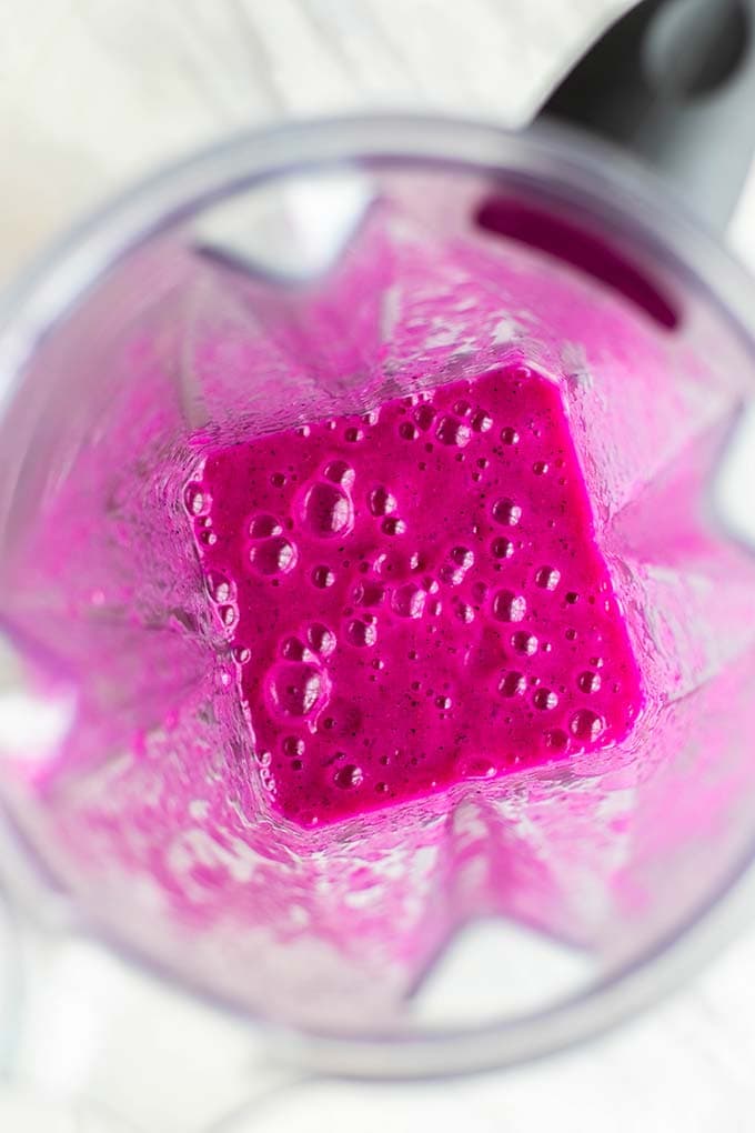 Looking down in a blender at pureed dragonfruit and mango.