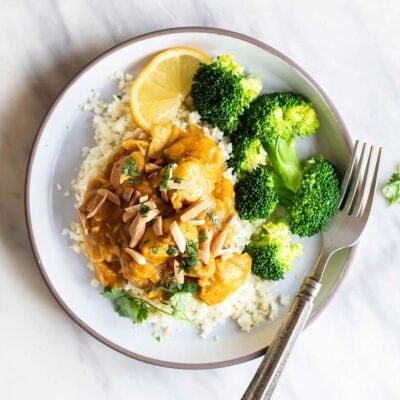 A white plate with a serving of crockpot pumpkin chicken garnished with cilantro.