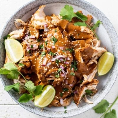 A bowl of slow cooker chicken mole garnished with limes.