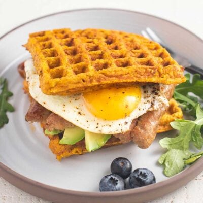 A white plate with a waffle sandwich and blueberries.