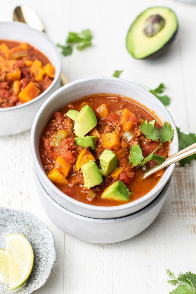 A bowl of Whole 30 chili shown with a gold spoon and garnished with avocado.