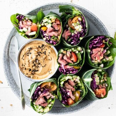 A plate with thai steak salad wraps on a plate with a creamy sunflower dipping sauce.