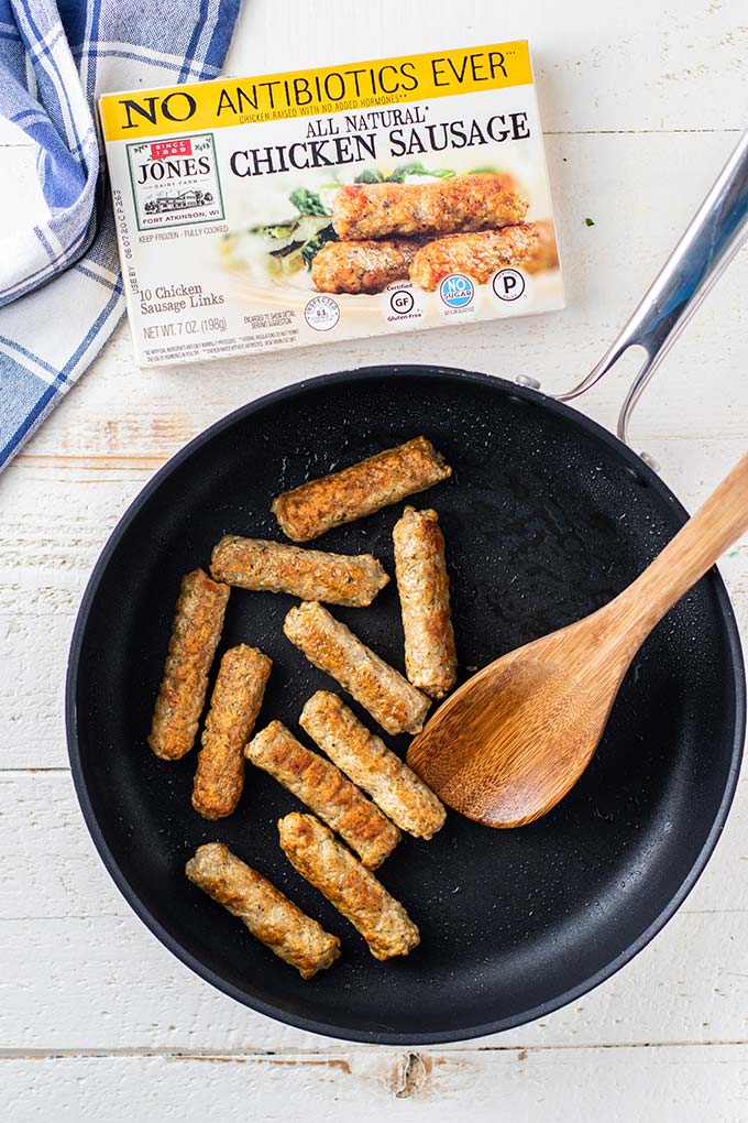 Chicken sausages browning in a skillet.