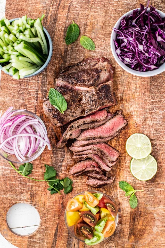 Thinly sliced rare steak surrounded by chopped veggies.