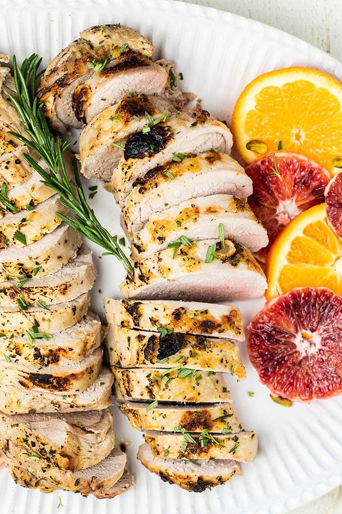 A closer up of a platter with sliced pork tenderloin served with blood oranges and mandarins.