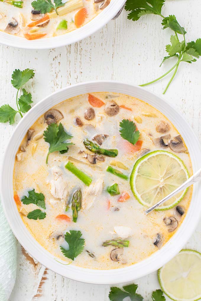 An close up look at the veggies and garnished on a bowl of tom kha gai soup recipe.