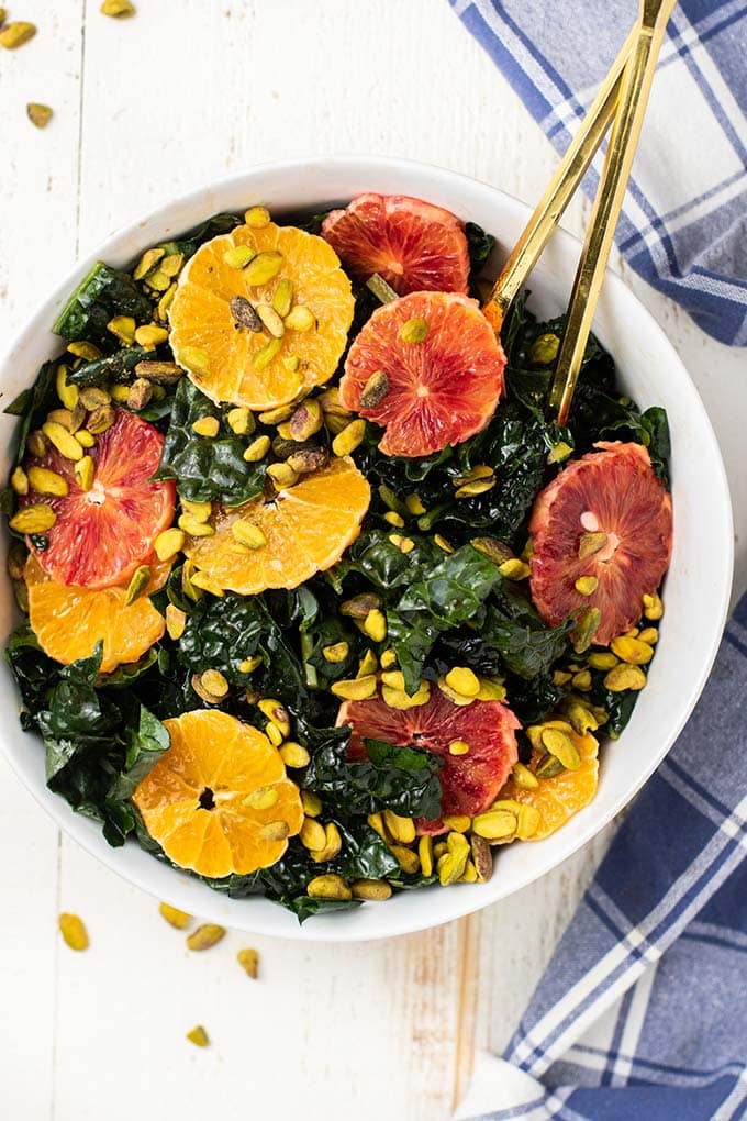 A close up look at a massaged kale salad with citrus and pistachios.