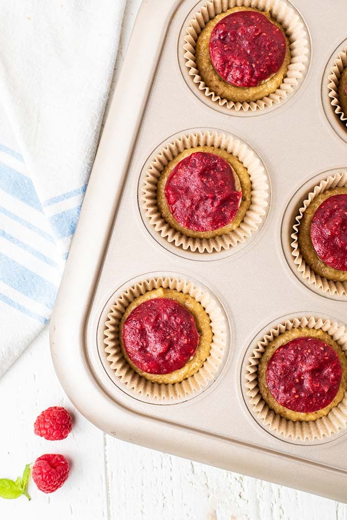 A muffin tin showing how to layer the batter and nut butter and jelly filling.