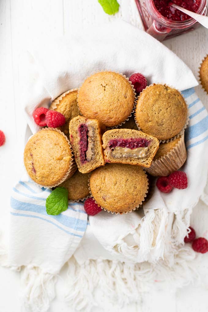 A basket of muffins with one cut open to show the nut butter and jam filling.