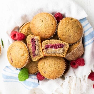 A basket of muffins with one cut open to show the nut butter and jam filling.