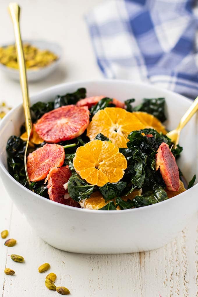 Massaged kale in a bowl being topped with blood orange and tangerine slices.