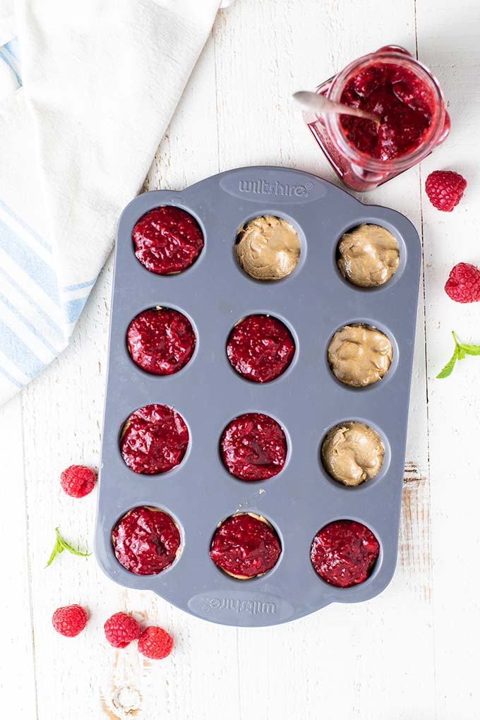 A mini muffin pan showing how to make the nut butter and jelly centers for this stuffed muffin recipe.