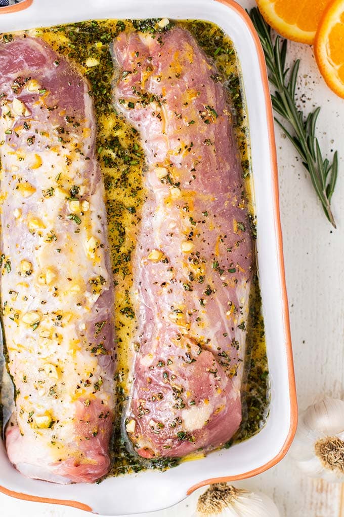 Two pork tenderloins marinating in a garlic, citrus and rosemary mixture.