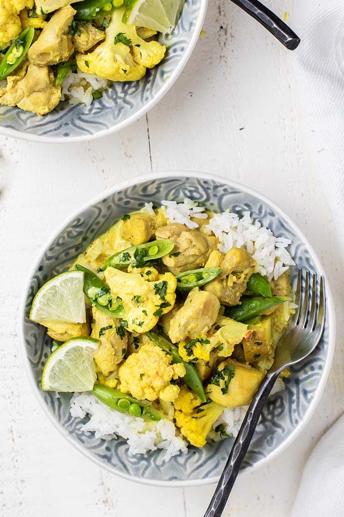 Two bowls filled with white rice and a thai chicken curry.