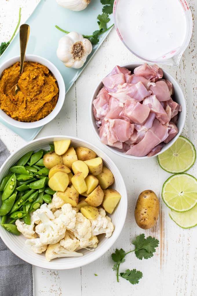 The ingredients for a yellow Thai curry showing the vegetables, chicken, coconut milk, and curry paste.