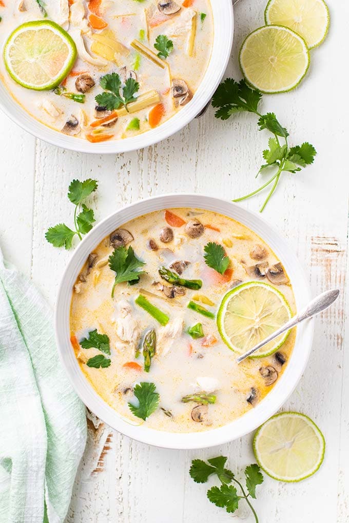 Two bowls of paleo coconut milk soup with chicken and asparagus.