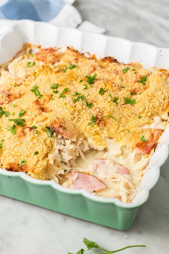 A green and white baking dish with a chicken cordon bleu casserole, shown with a crunchy breadcrumb topping.