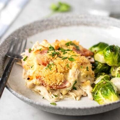 A slice of chicken cordon bleu casserole on a plate with brussels sprouts.